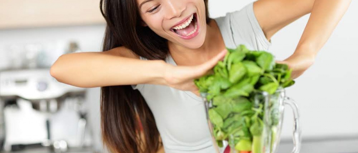 Eine Frau steckt Lebensmittel, die glücklich machen, in einen Mixer