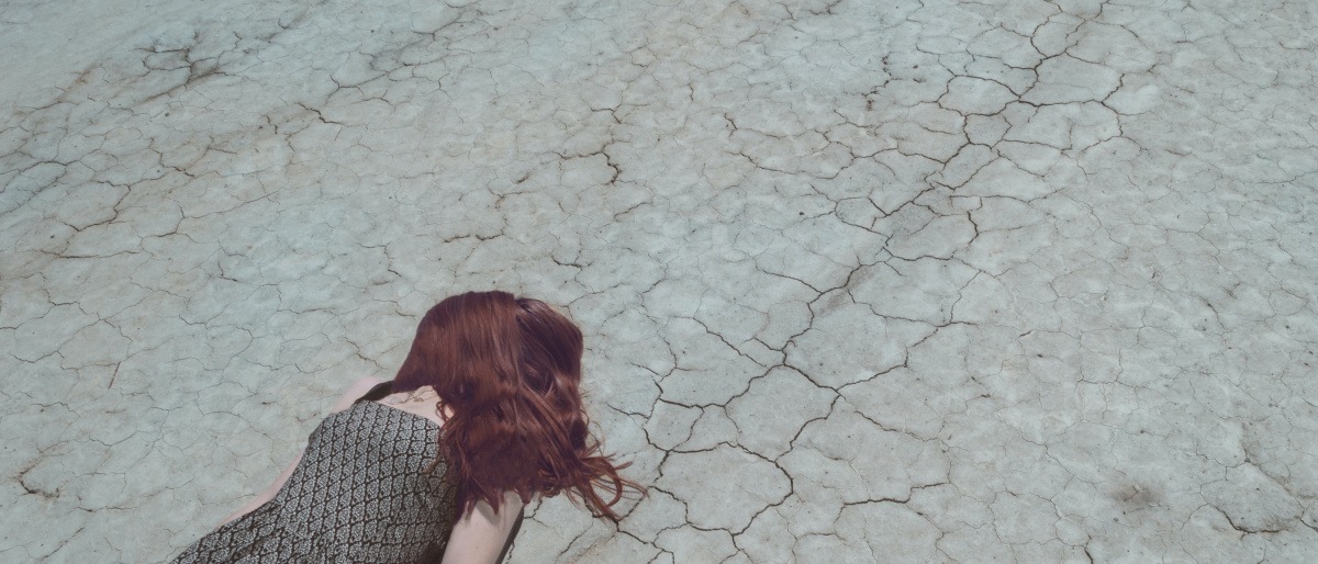 Eine Frau, die ihren Lebenssinn verloren hat, liegt auf einem ausgetrockneten Wüstenweg.