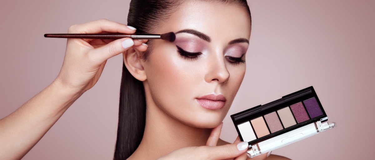 Ein Making off, wo einer Frau mit dunklen langen braunen Haaren ein Augen Make-up geschminkt wird