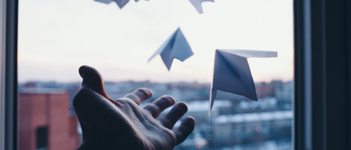 Hand die Papierflieger fliegen lässt