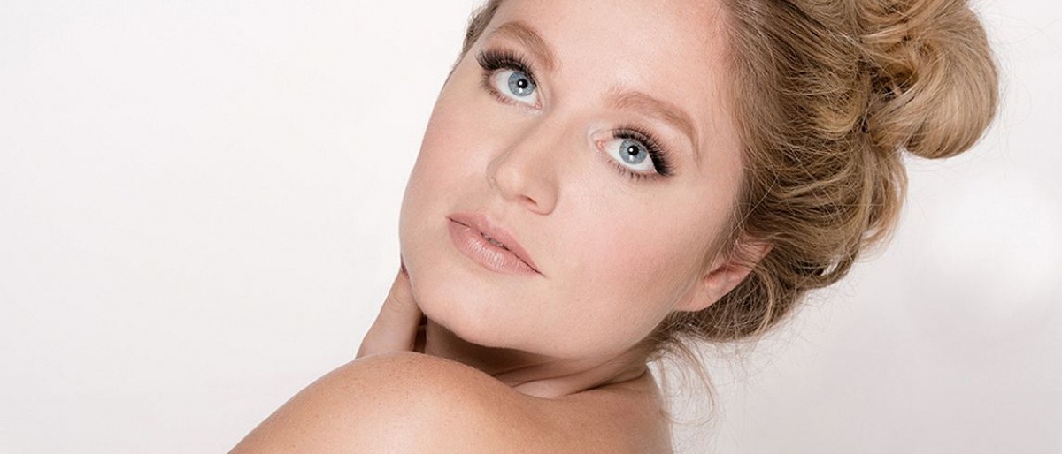 Eine Frau mit blonden langen Haaren mit traumhaft langen schönen Wimpern von Luxuslashes