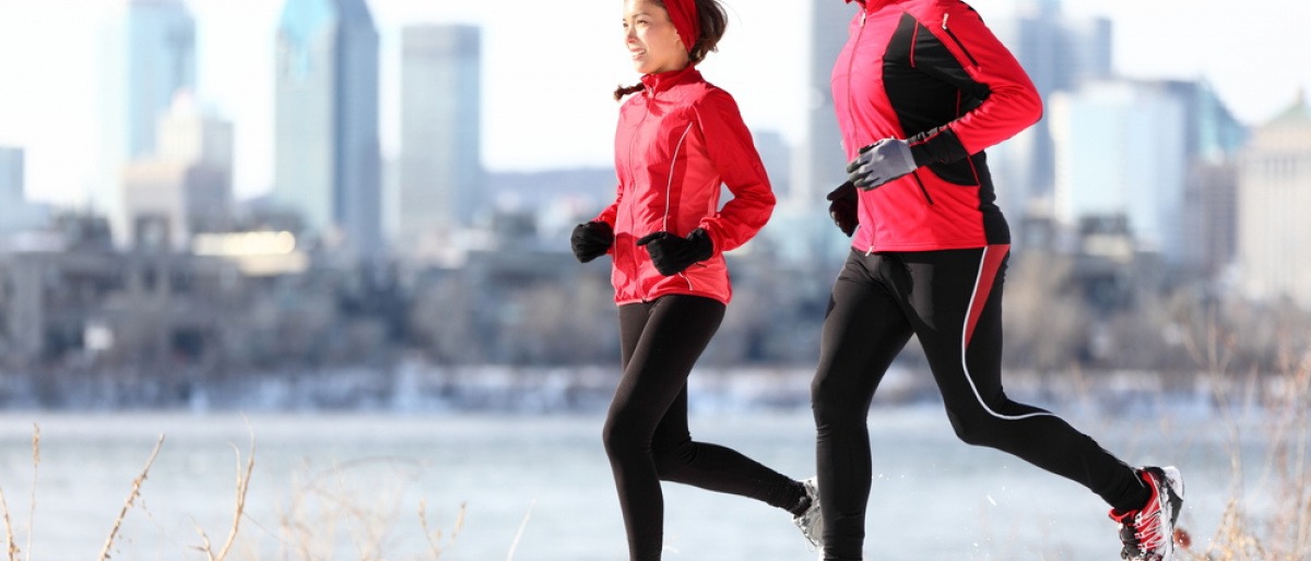 Ein Mann und eine Frau joggen vor einer winterlichen Stadt