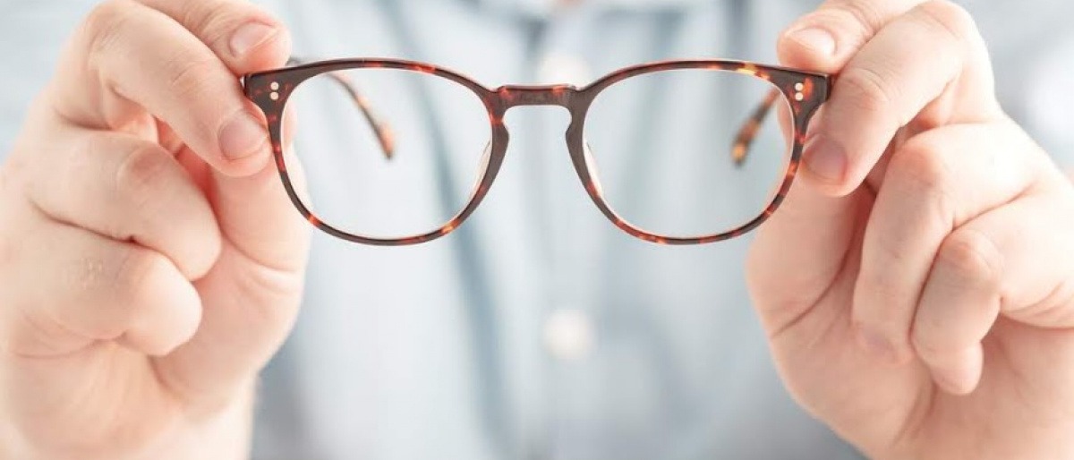 Ein Mann hält eine braune Brille in der Hand