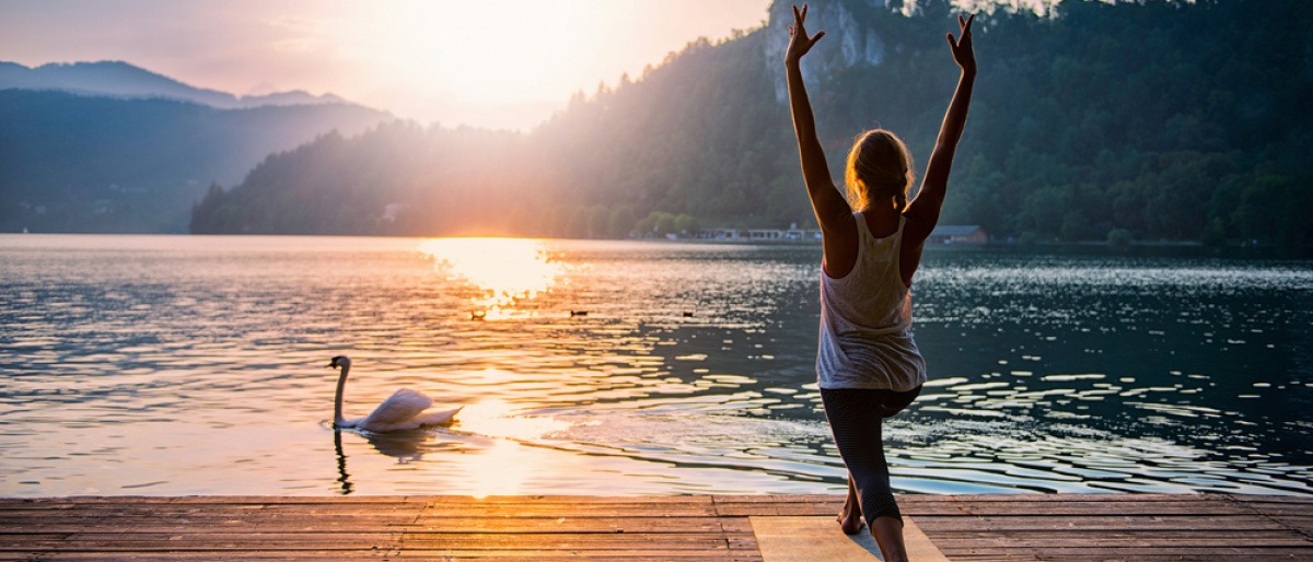 Eine Frau meditiert neben einem See in der Natur