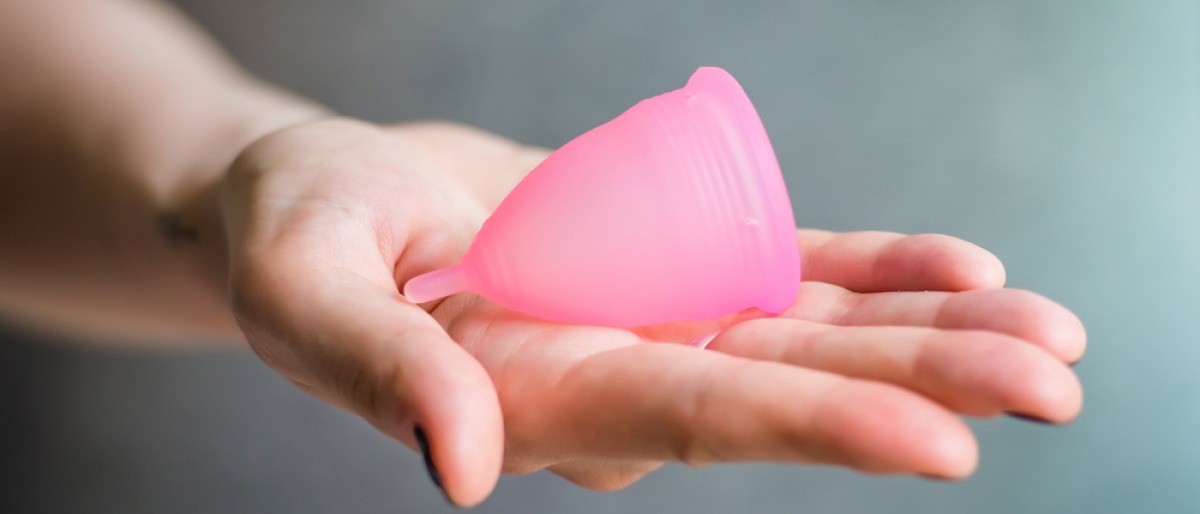 Eine Frau hält eine Menstruationskappe für den Urlaub