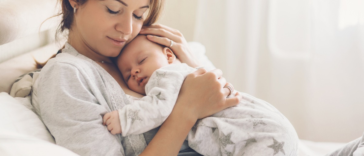 Eine Frau hält ihr Baby und denkt über ein Mommy Makeover nach