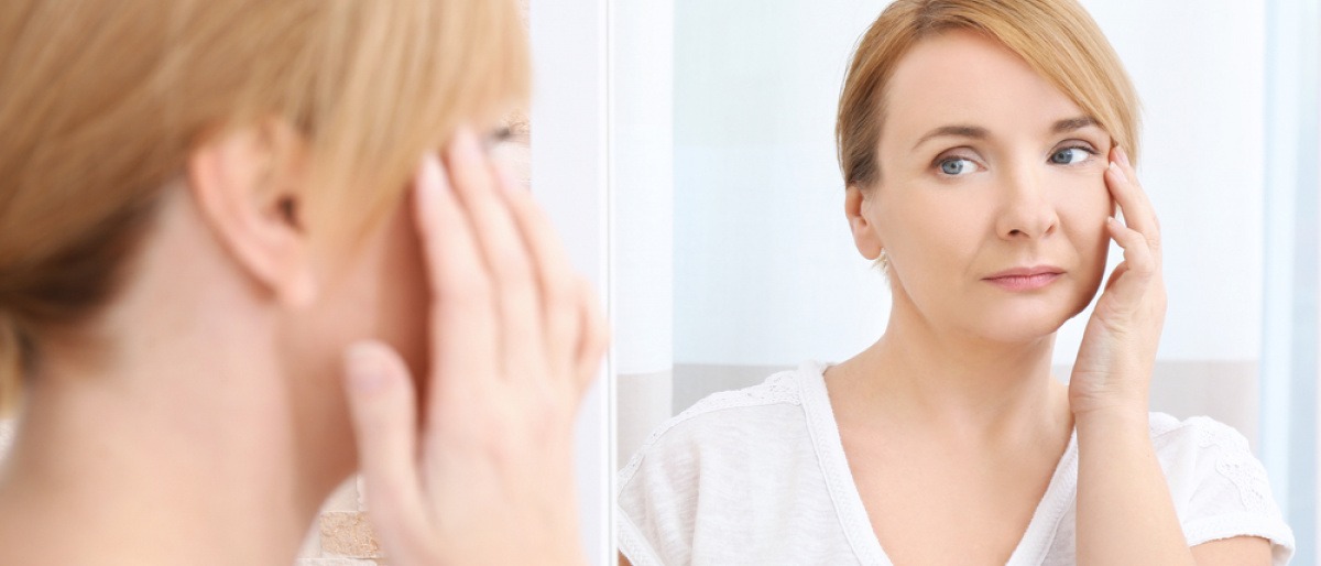 Eine Frau betrachtet im Spiegel ihre müden Augen