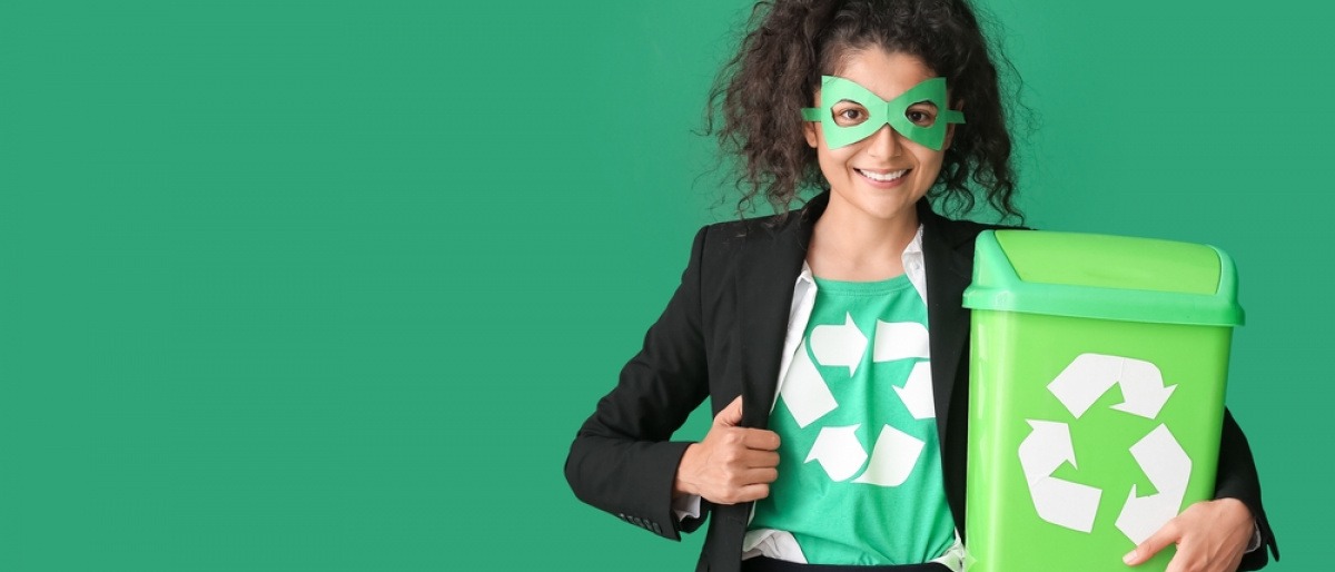 Frau gekleidet als Öko-Superheld mit Mülltonne auf grünem Hintergrund.