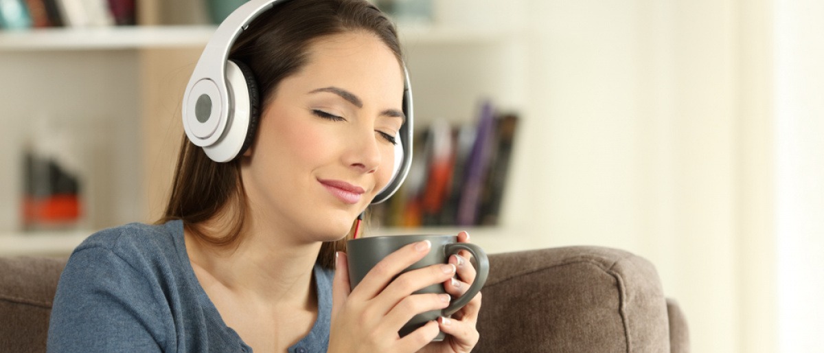 Eine junge Frau hört mit Kopfhörern Musik und genießt es