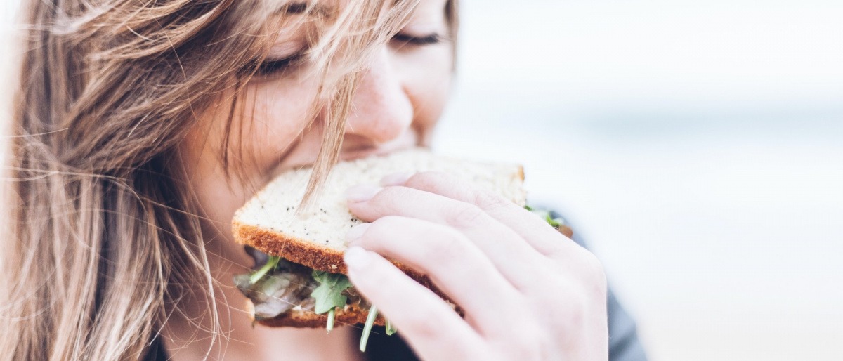Eine Frau beißt in ein Sandwich mit Salat