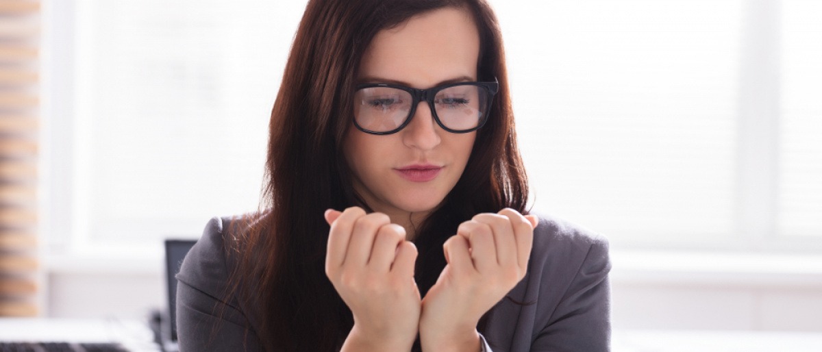 Eine Frau betrachtet ihre Nagelpsoriasis und überlegt, was tun?