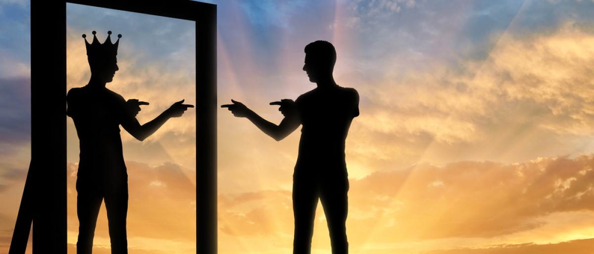 Die Silhouette eines Mannes, der sich selbst mit einer Krone auf seinem Kopf im Spiegelbild sieht und anfeuert - typisch für eine Narzissten Beziehung.