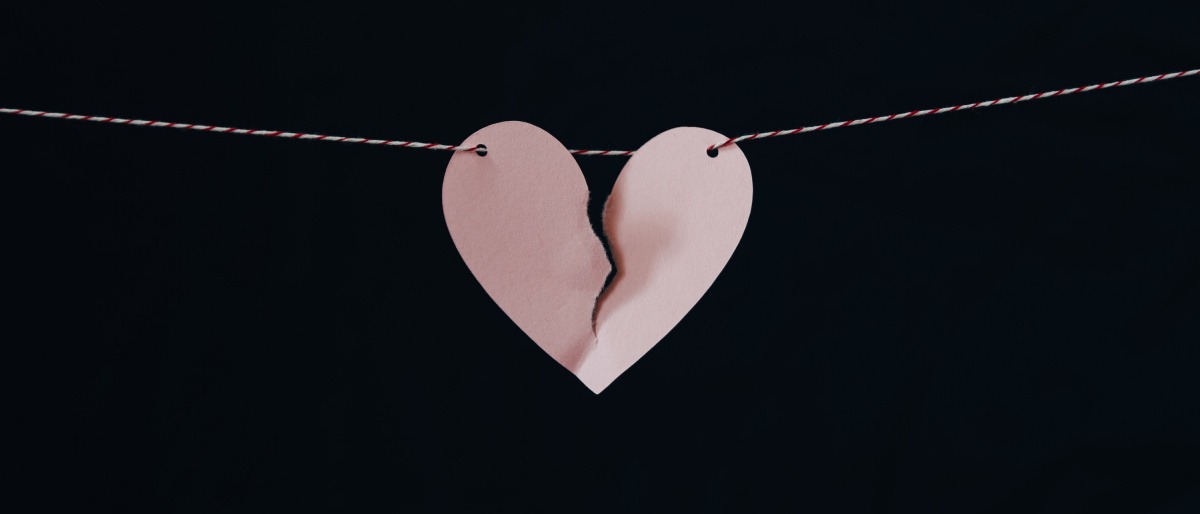 Ein eingerissenes Herz aus Papier hängt aufgespannt an einer Kordel. 