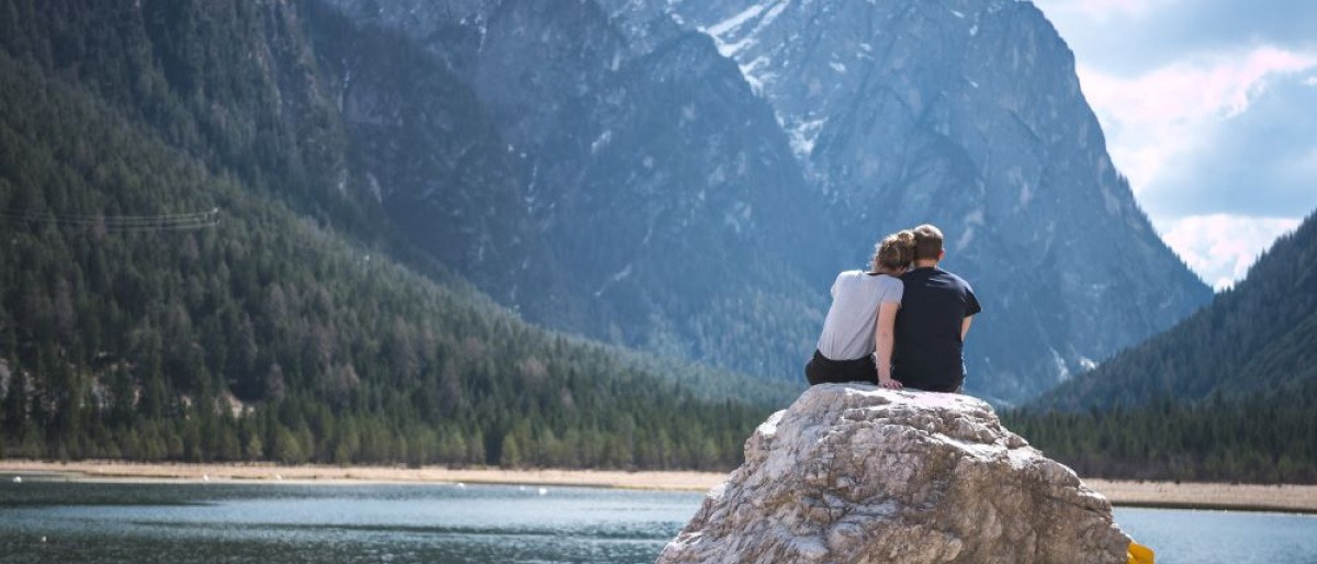 Ein Paar sitzt auf einem Felsen am See und kommuniziert
