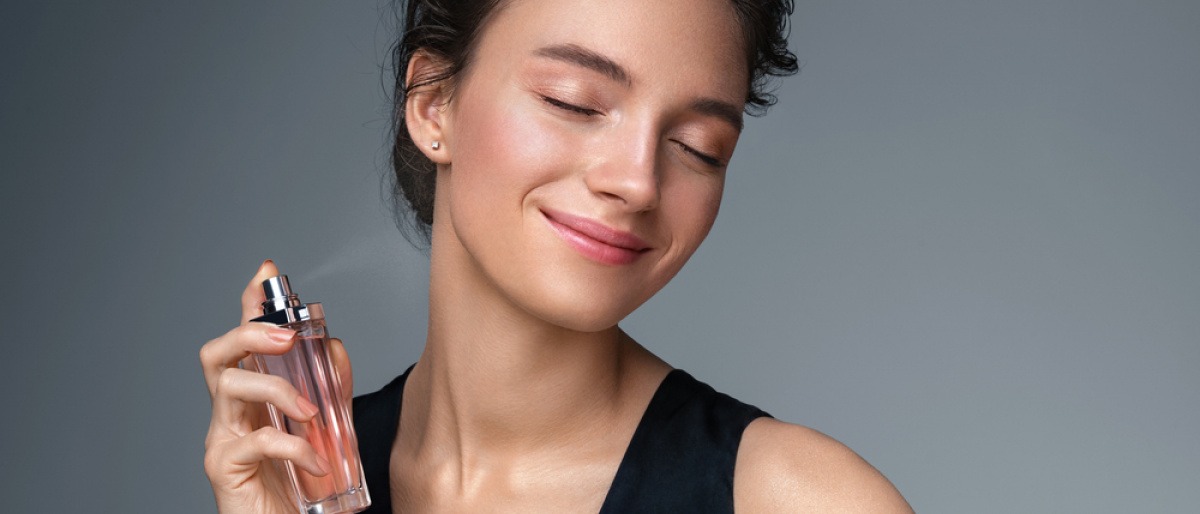 Frau sprüht sich mit Parfum ein
