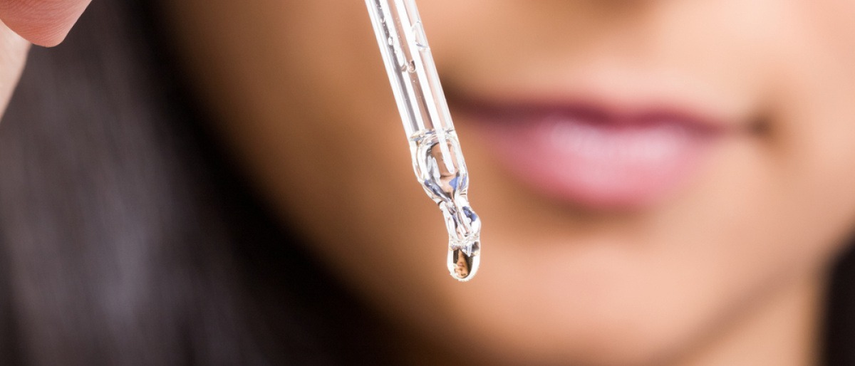 Eine Frau gibt Öl mit einer Pipette auf die Hand