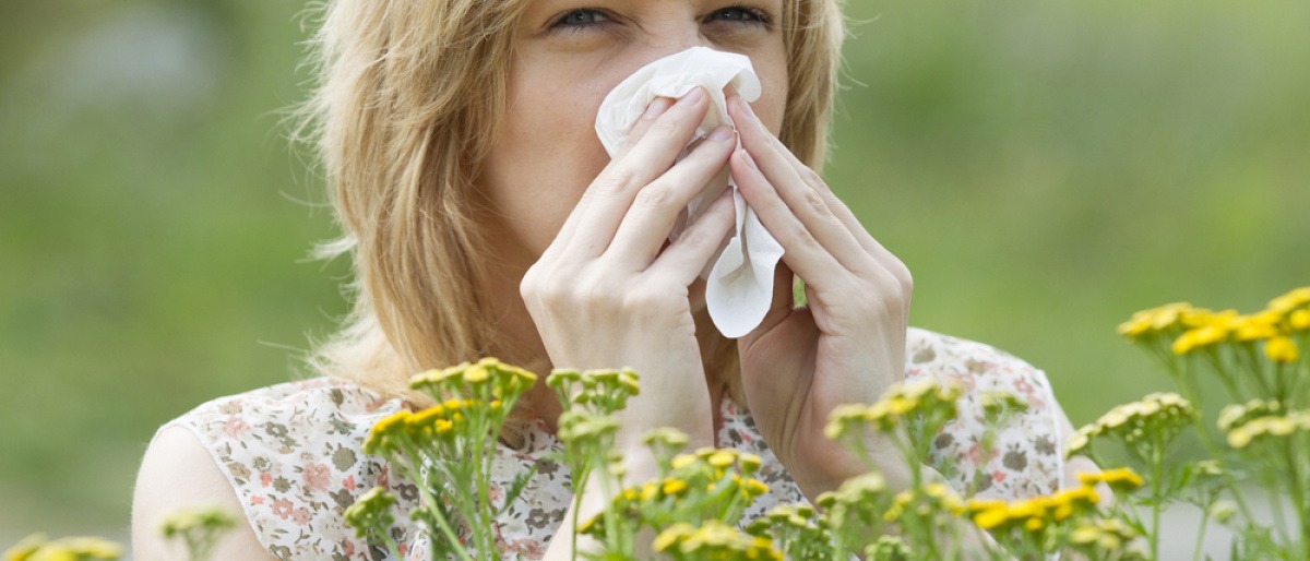 Pollenallergie Symptome zeigt eine Frau, die in einer Wiese steht