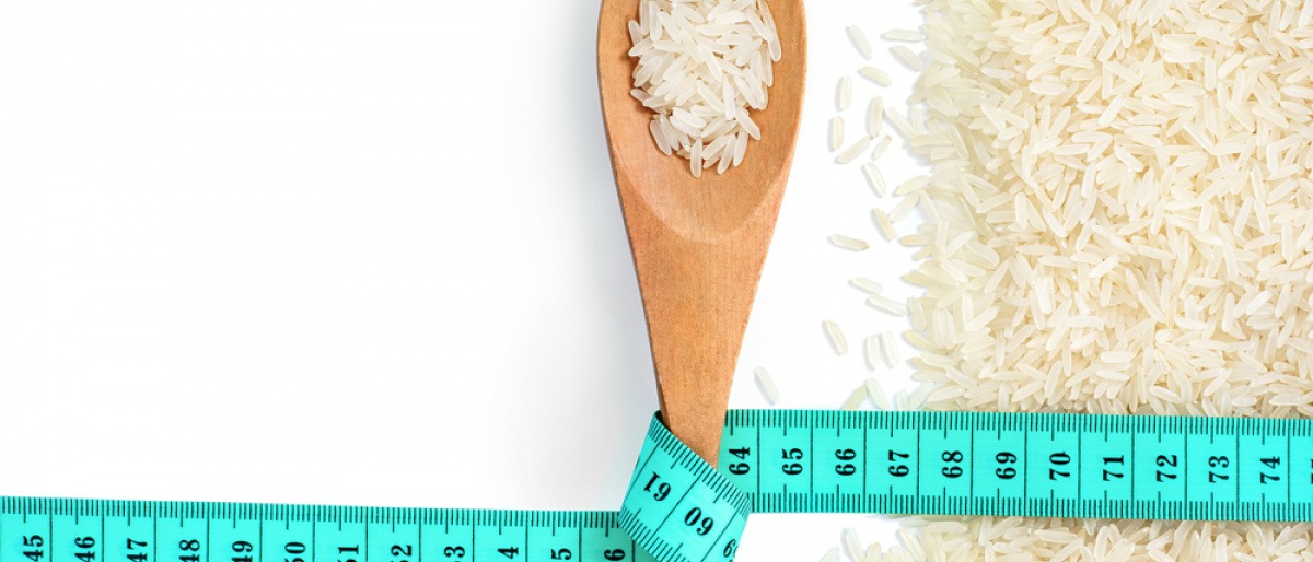 Reis zum Abnehmen auf einem Löffel mit einem Maßband