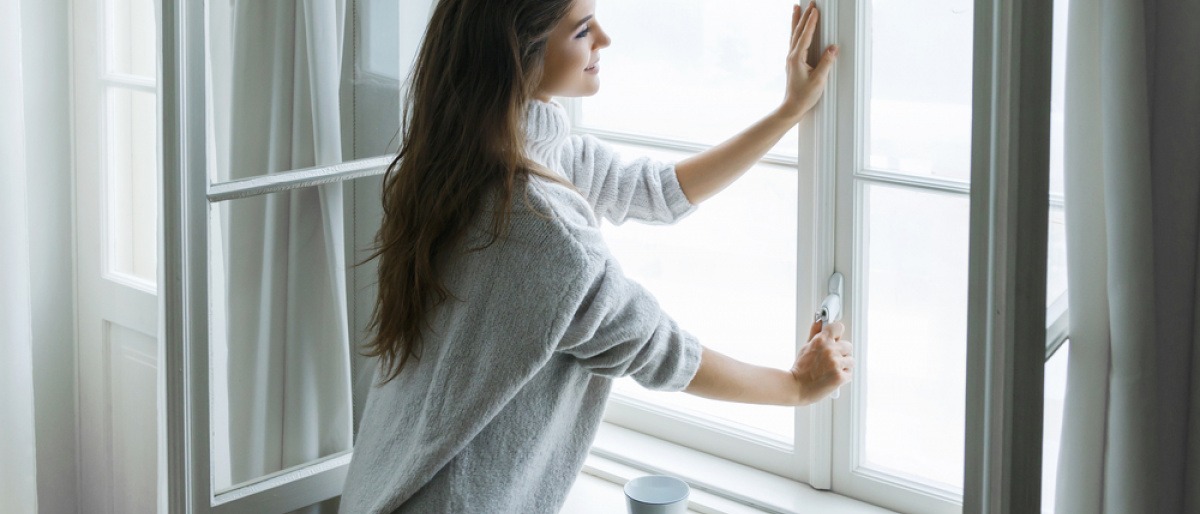 Eine Frau öffnet ein Fenster um richtig zu lüften