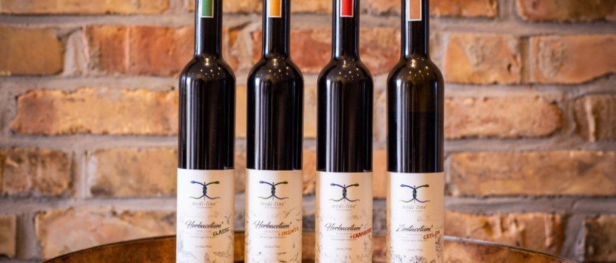 Flasche mit Rotweinessig und Weintrauben im Hintergrund