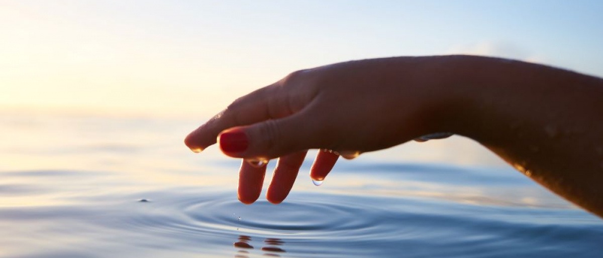 Ruhige Kreise im Wasser werden durch einen Finger gezogen