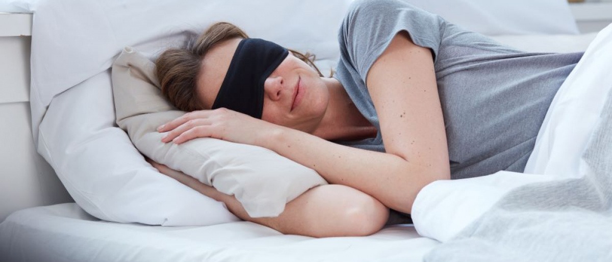 Eine Frau im Bett trägt eine Schlafmaske für erholsamen Schlaf