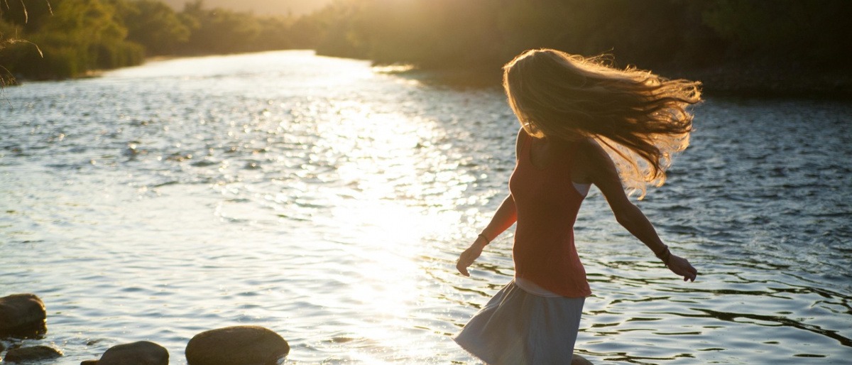 Eine Frau steht ohne Schmerzen im Wasser und wirkt glücklich