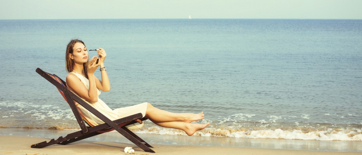 Frau schminkt sich am Strand