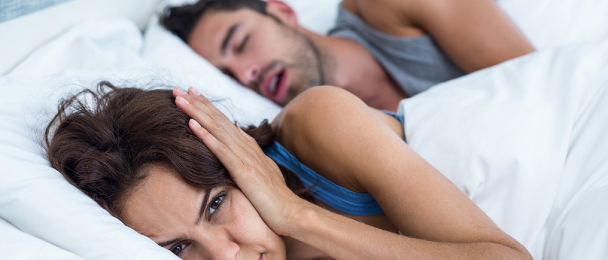 Ob Gurgeln gegen Schnarchen dieser Frau hilft, ihrem Partner das lästige problem abzugewöhnen? Sie liegt im Bett und hält sich die Ohren zu.