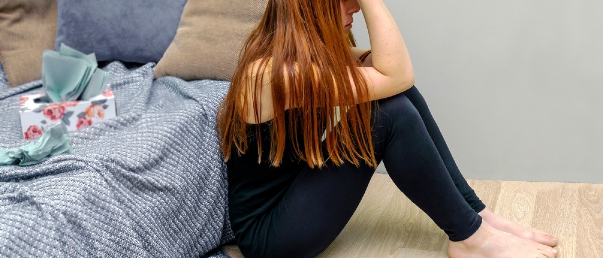 Schuldgefühle nach Trennung - traurige Frau sitzt auf Boden und versucht, ihre Trennung zu verarbeiten.