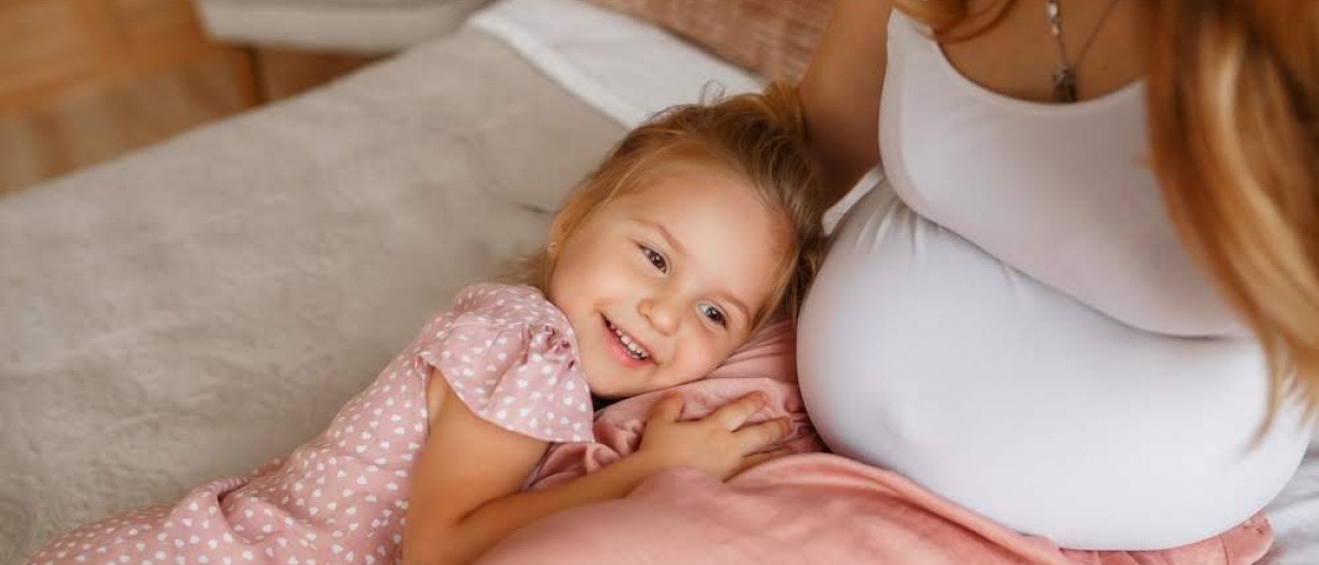 Ein Kind lehnt am Bauch einer schwangeren Frau