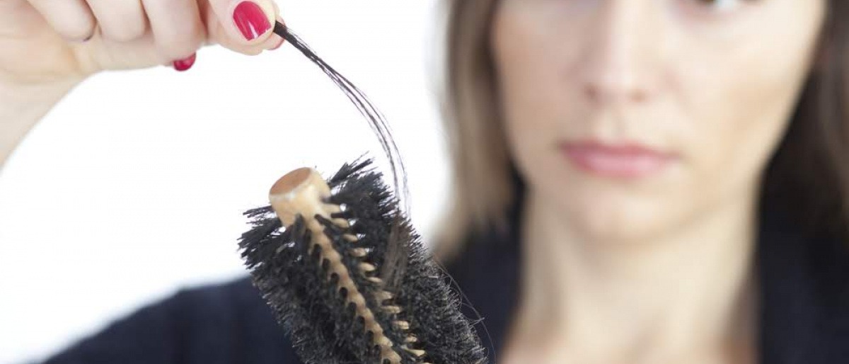 Naturhaarbürste säubern - man sollte wissen wie Eine Frau im Hintergrund, die sich ein Haar aus der verschmutzten Rundbürste gerissen hat