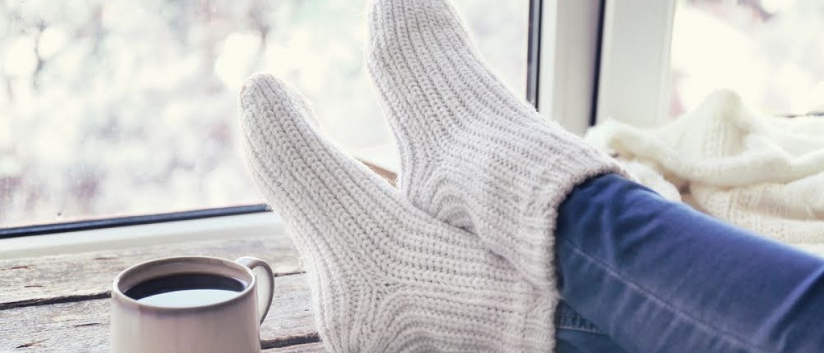 Beine mit Wollsocken sind neben Tee am Tisch