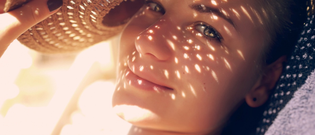 Frau mit Hut und Punkten von der Sonne im Gesicht