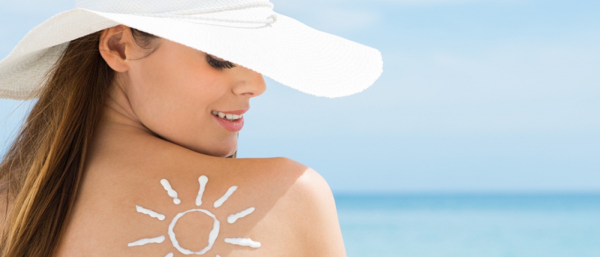 Frau am Strand mit Sonnencreme auf der Schulter