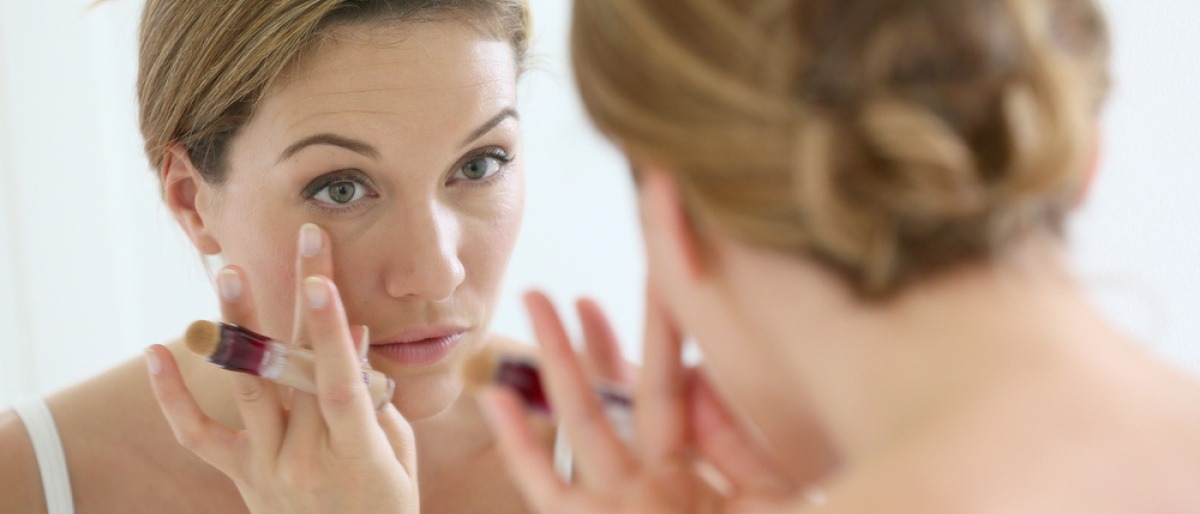 Eine Frau sieht ihre Augen im Spiegel an und benötigt Anti Aging Tipps