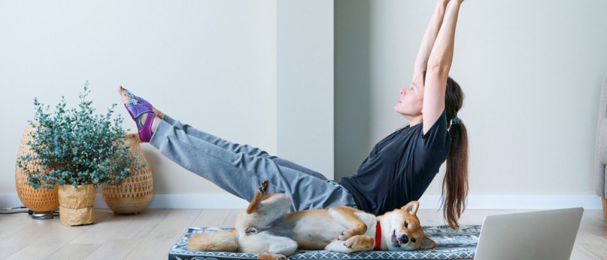 Sport mit Hund - Frau macht mit ihrem Hund Sport im Wohnzimmer.