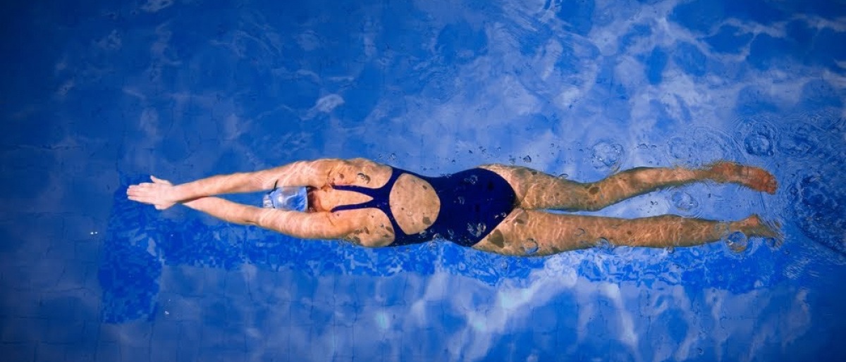 Eine Aufnahme aus der Vogelperspektive auf eine Frau, die in einem Swimmingpool schwimmt. 