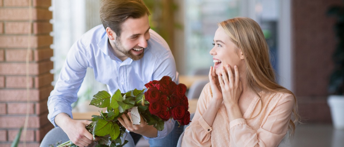 Mann schenkt einer Frau rote Rosen als Zeichen der Liebe