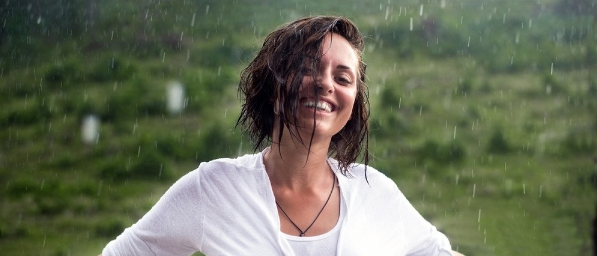 Frau mit starkem Immunsystem steht glücklich im Regen