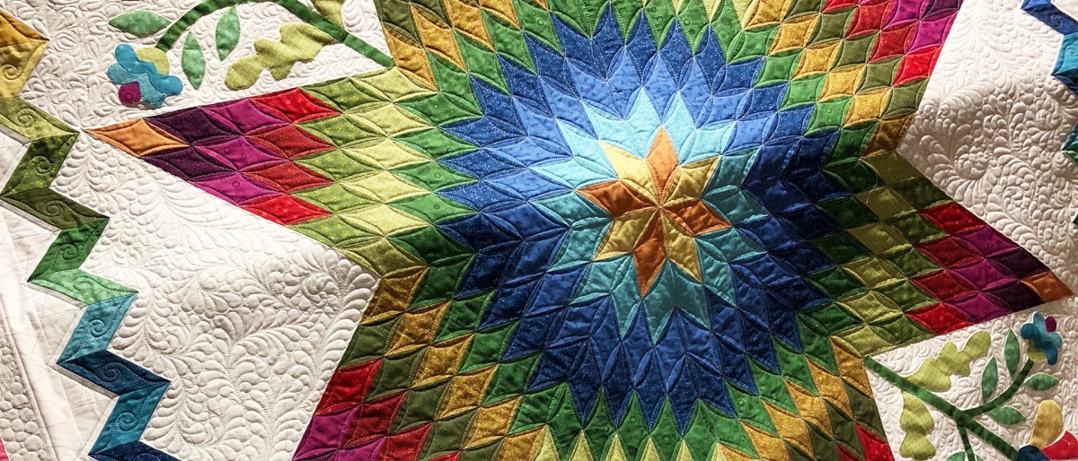 Eine Patchwork Tagesdecke zeigt einen Stern und Blumen