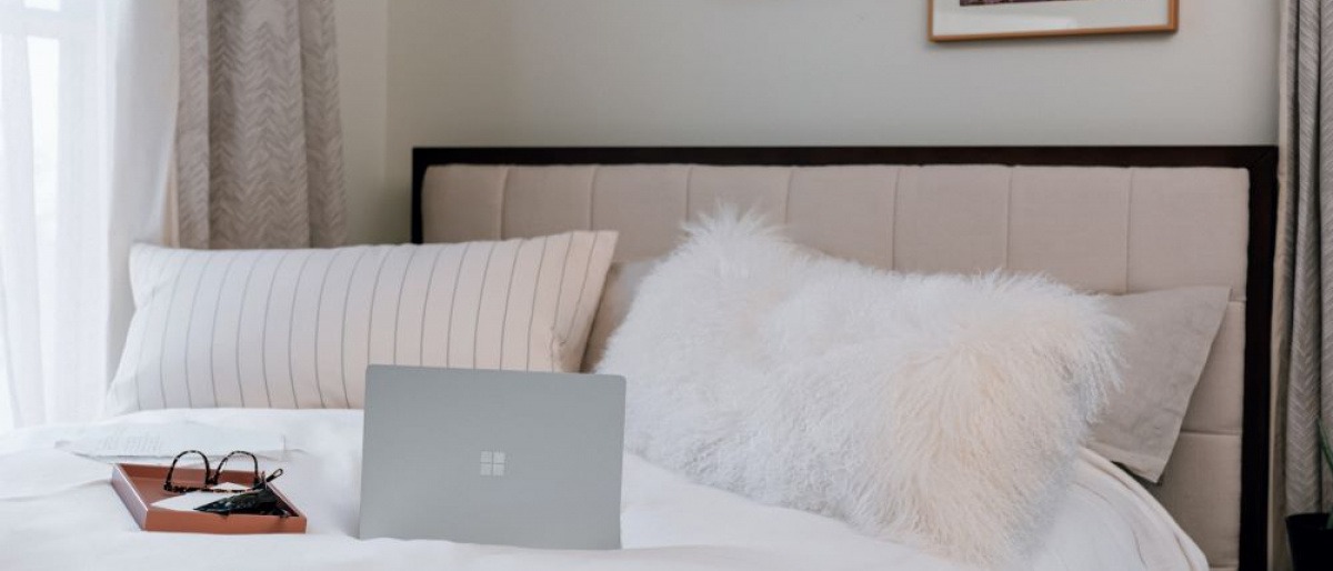 Auf einem Bett liegt ein Laptop als Störquelle im Schlafzimmer