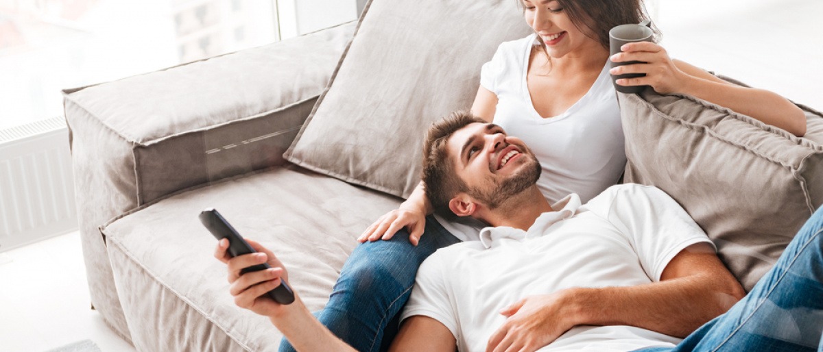 Ein Paar sitzt auf der Couch, die Fernbedienung in der Hand