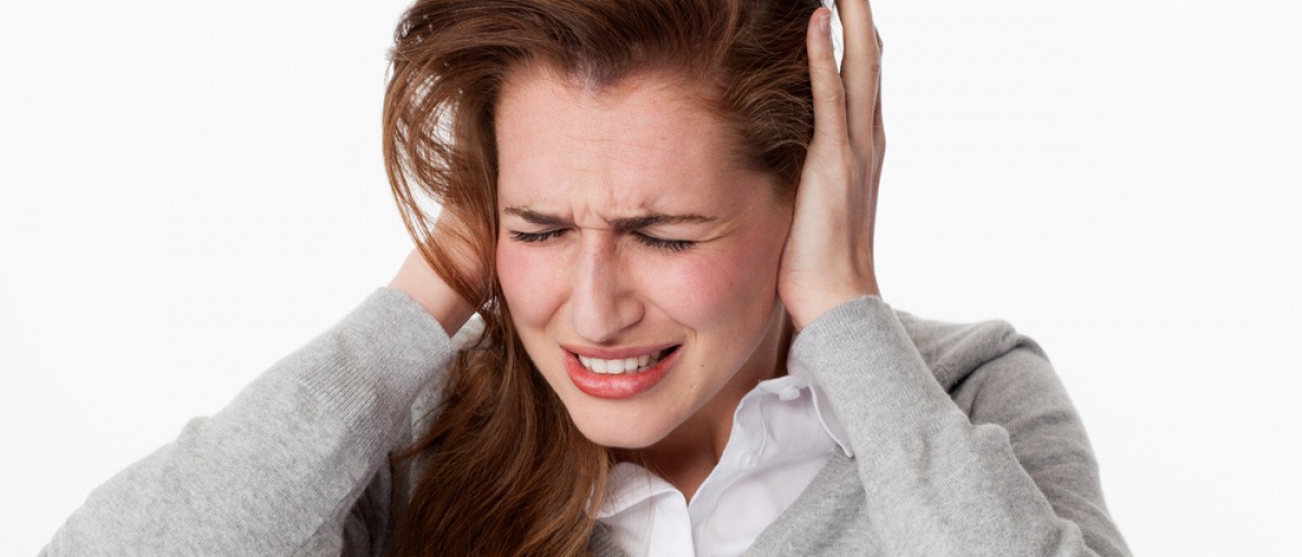 Eine Frau hält sich die Ohren zu und fragt was tun gegen Tinnitus
