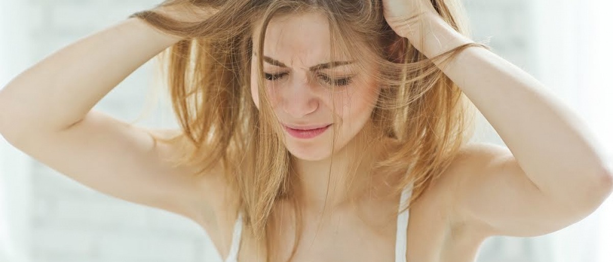 Eine Frau kratzt ihre trockene Kopfhaut