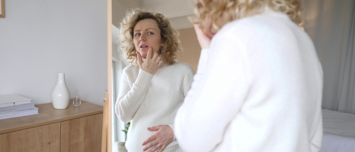 Schwangere Frau ohne unreine Haut vor dem Spiegel