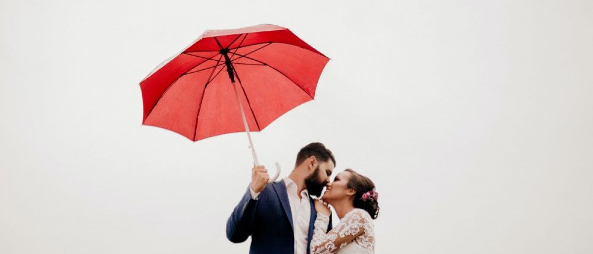 Ein Mann küsst eine Frau, in der Hand einen Regenschirm, um Sicherheit zu vermitteln