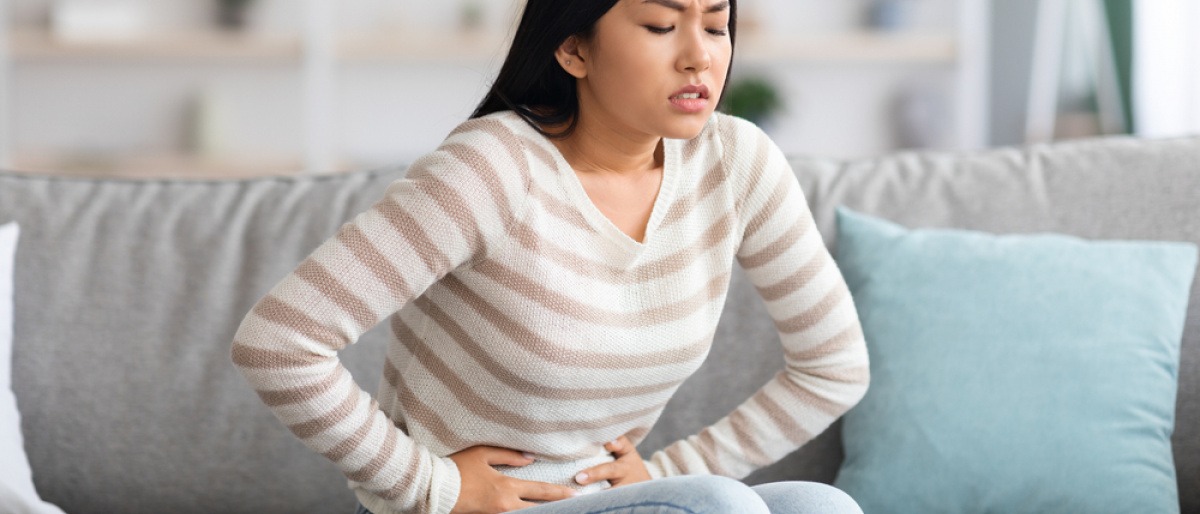 Frau mit Magenschmerzen durch Verstopfung am Sofa