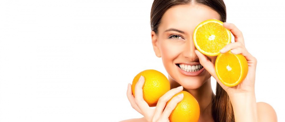 Frau mit Orangen vor dem Gesicht.
