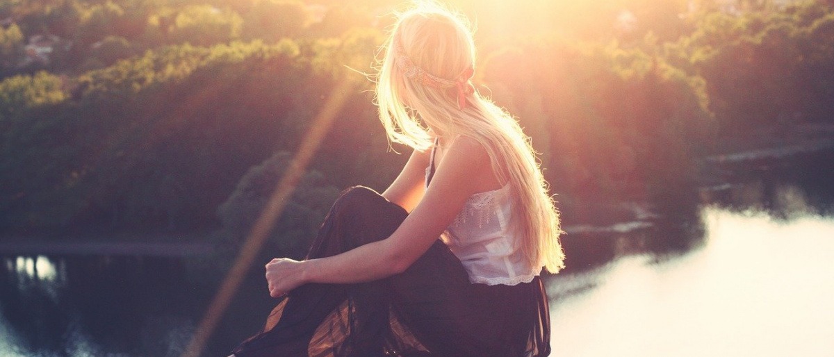 Junge Frau sitzt in der Sonne und kann Vitamin D Mangel beheben